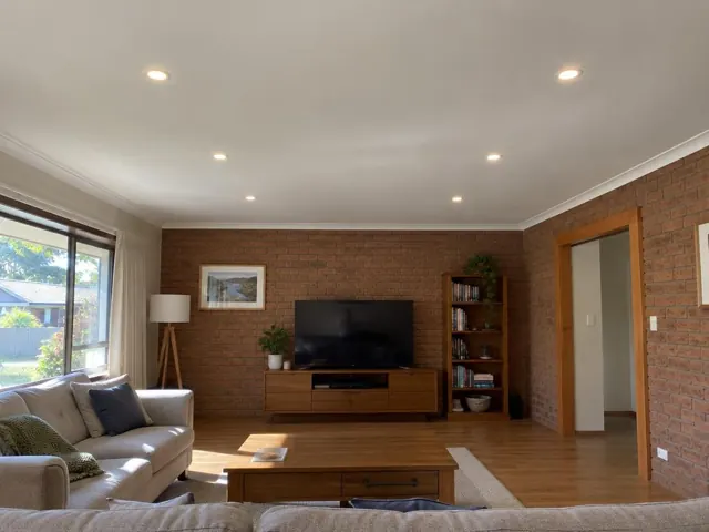 Living room with flush ceiling downlights, brick walls and timber flooring in Cardiff Heights